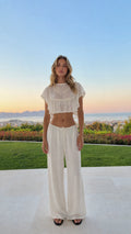 Front view of woman wearing white ruffled crop top and wide-leg pants set