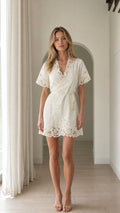 Model wearing white lace trim wrap mini dress front view