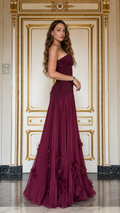 Side view of burgundy strapless pleated maxi gown with floral hem detail