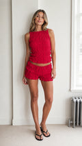 Model wearing the red textured crop top and ruffle shorts set, front view