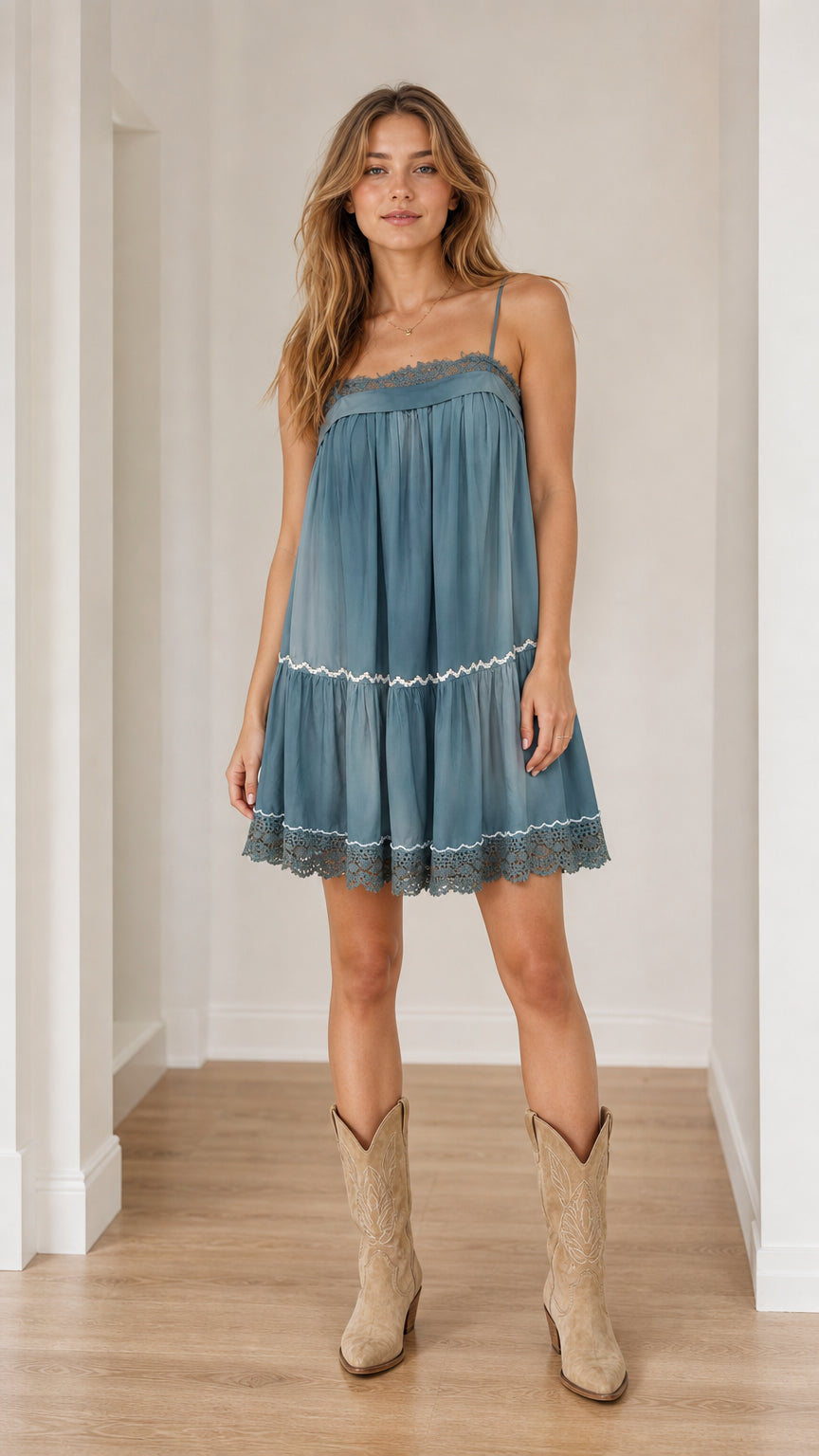 Front view of model wearing blue boho tiered camisole dress with cowboy boots