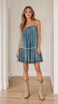 Front view of model wearing blue boho tiered camisole dress with cowboy boots