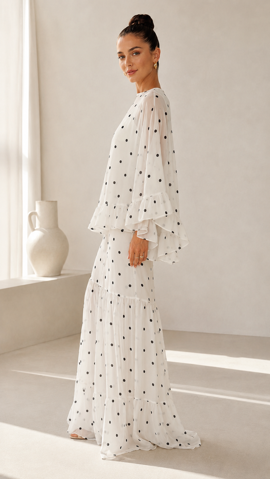 Side view of white polka dot maxi dress with sheer cape sleeves and ruffle cuffs