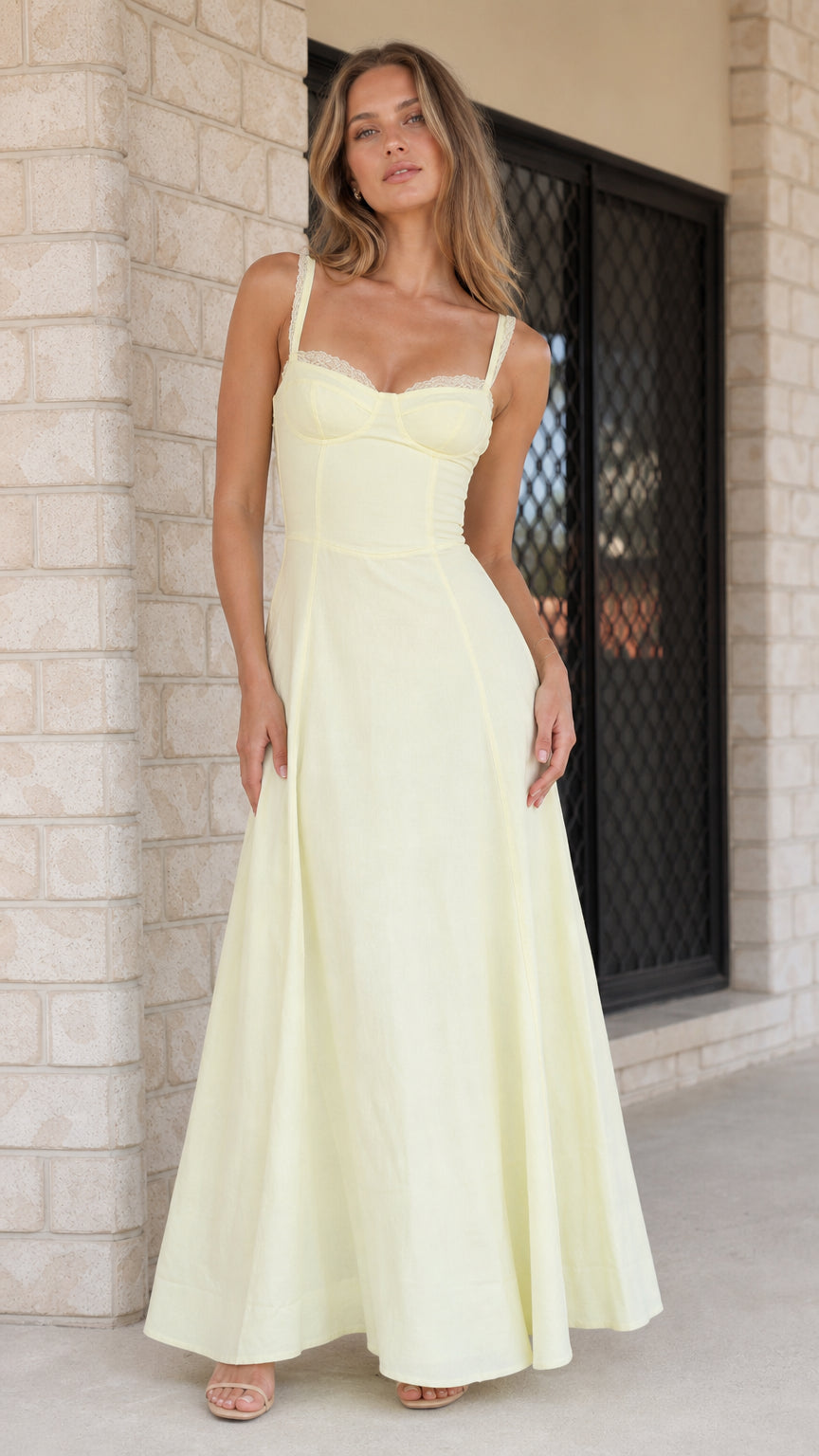 Front view of woman wearing yellow lace-trim corset maxi dress