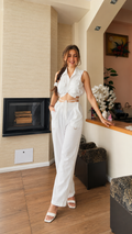 Front view of white sleeveless tie front crop top and wide leg pants matching set