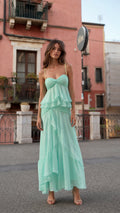 Front view of woman wearing mint ruffled tiered maxi dress in town square