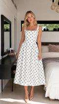 Front view of woman wearing white polka dot midi dress
