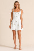 Front view of white embellished square neck mini dress with bow straps
