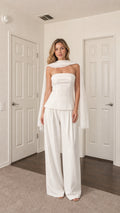 Front view of model wearing white strapless top, wide-leg pants, and scarf