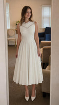 Front view of model wearing white lace trim midi dress with white heels