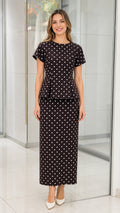 Front view of black polka dot peplum top and midi skirt set on model