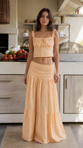 Front view of woman wearing peach eyelet crop top and tiered maxi skirt set