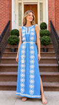 Front view of woman wearing blue embroidered sleeveless maxi dress on brick steps
