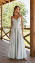 Front view of woman wearing white striped V-neck maxi dress on a wooden porch