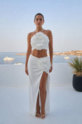 Front view of model wearing white 3D rose two-piece set against ocean backdrop