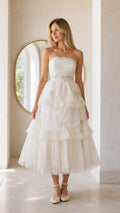 Front full view of woman wearing white strapless tiered midi dress