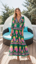 Front view of woman wearing green floral maxi dress on wooden deck