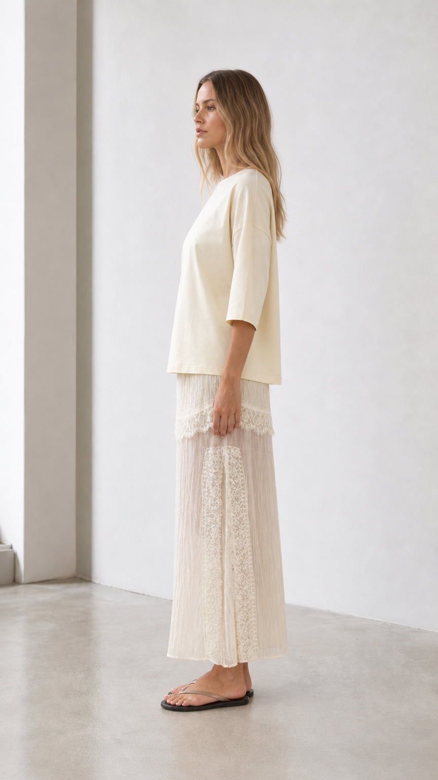 Side profile view of woman in cream two-piece outfit