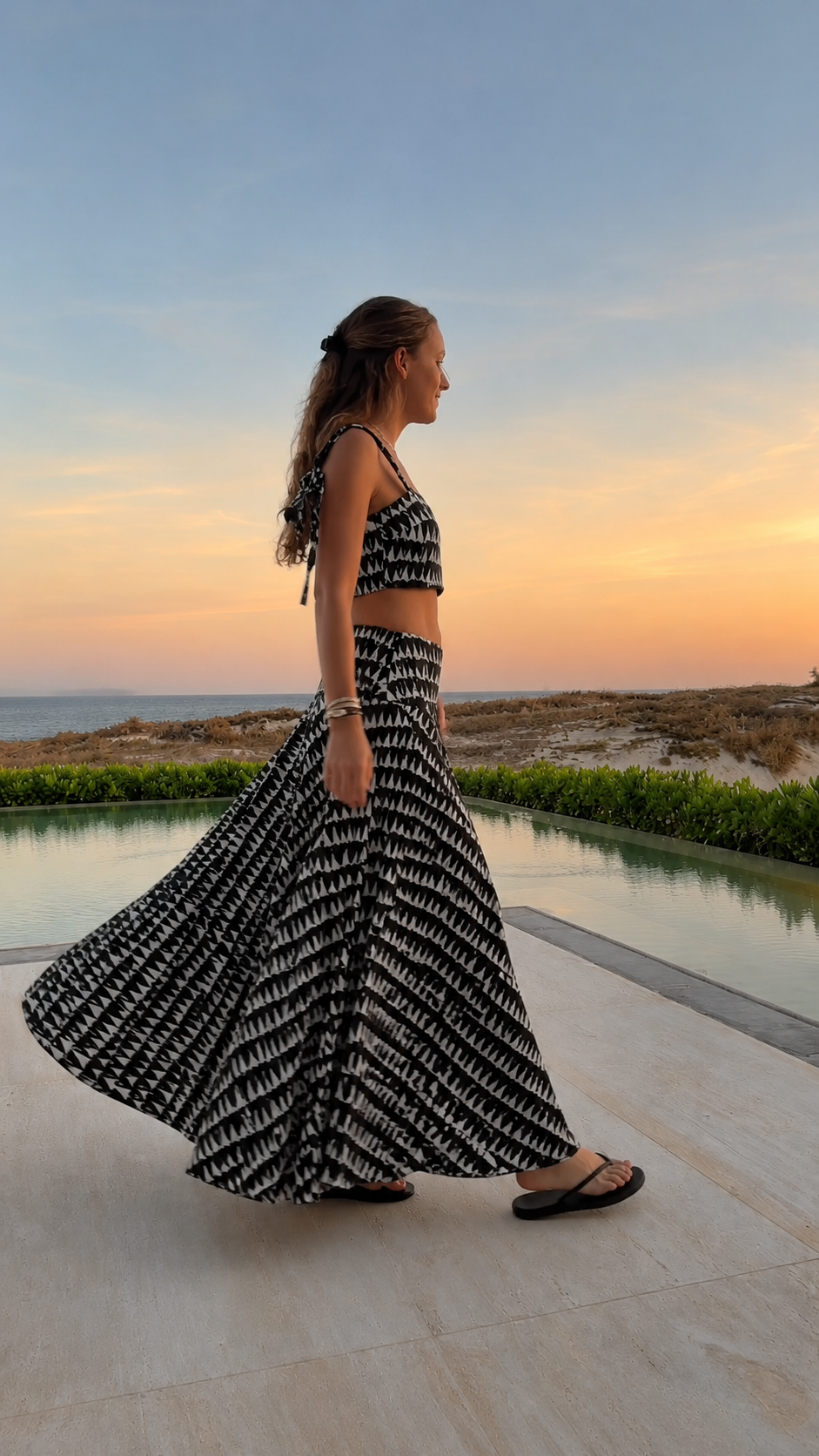 Side view of black printed crop top and flowing maxi skirt set