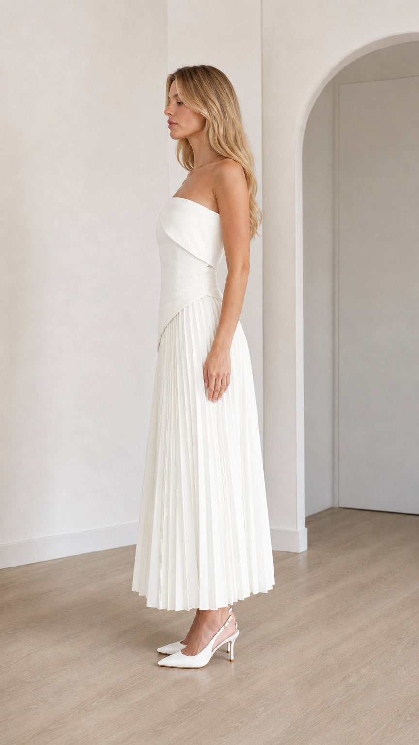 Side view of model in white pleated midi dress