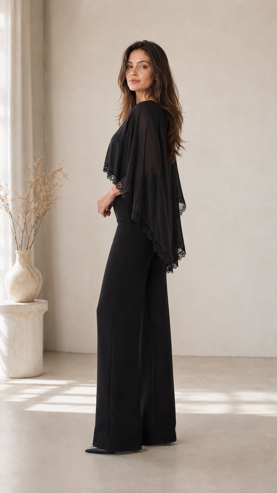 Side view of black elegant jumpsuit with flowing cape overlay and wide legs