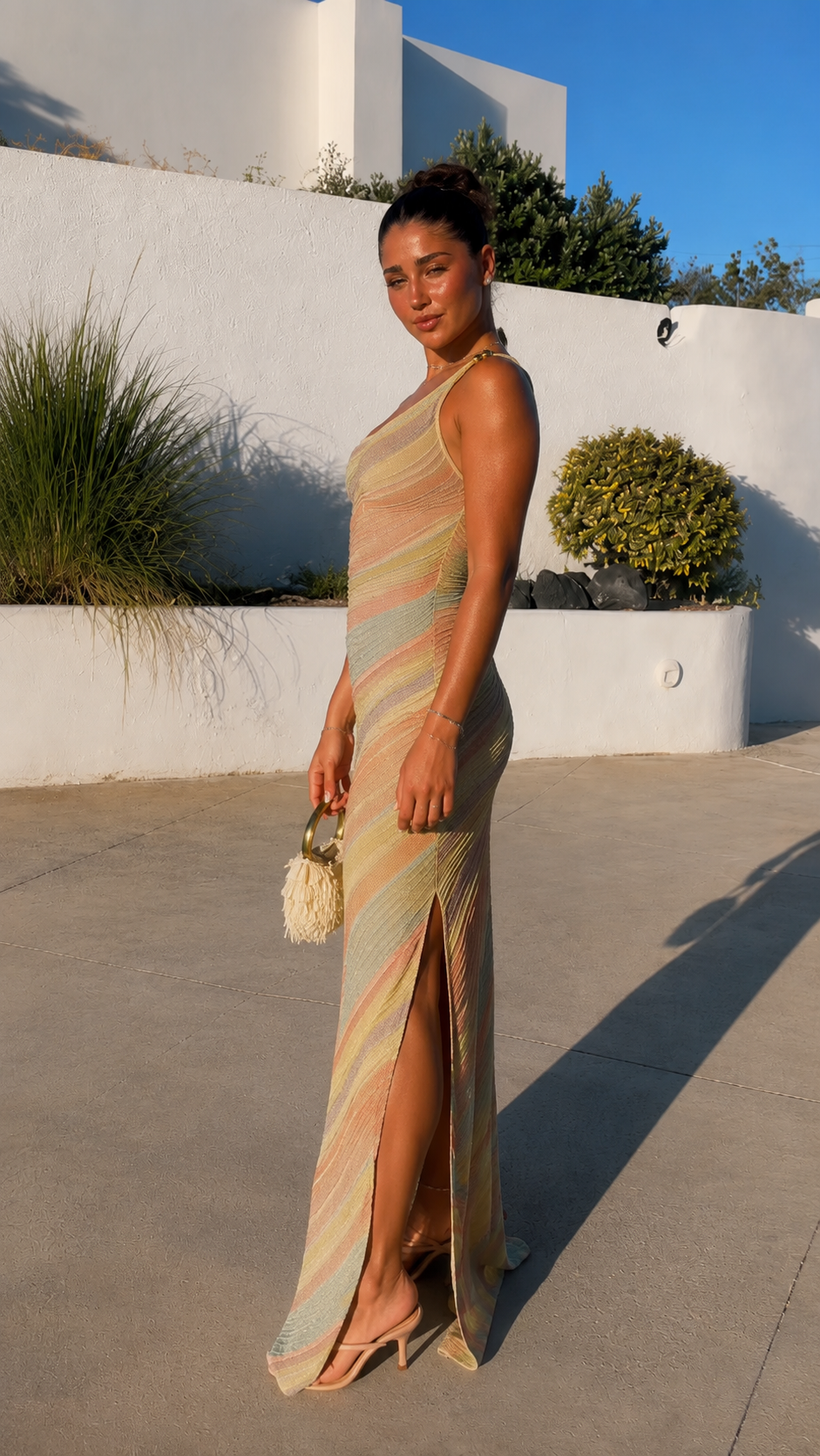 Side angle of pastel striped one-shoulder fitted maxi dress with high slit