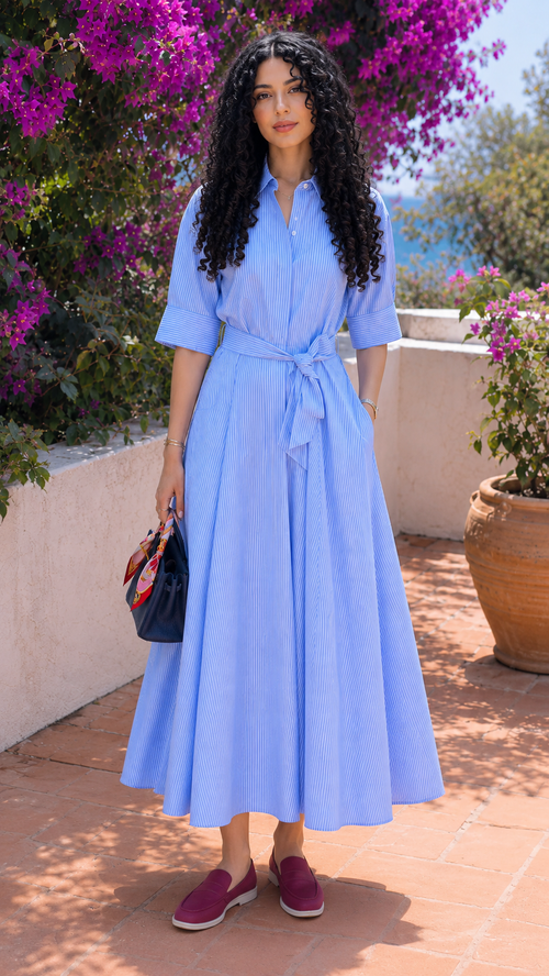 Woman wearing a sky blue striped belted shirt maxi dress with pleated skirt, front view