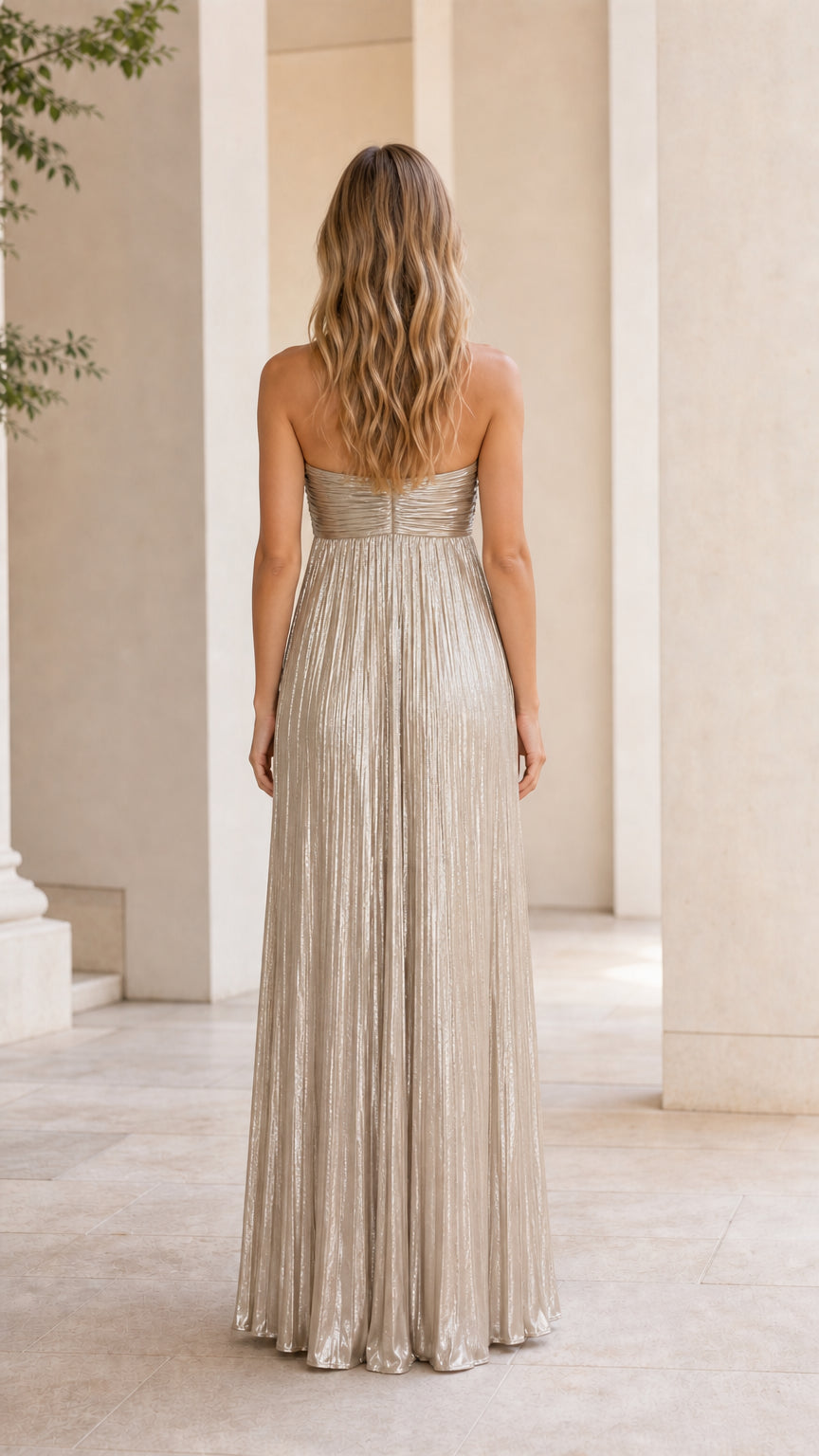 Back view of model wearing gold metallic pleated strapless maxi dress