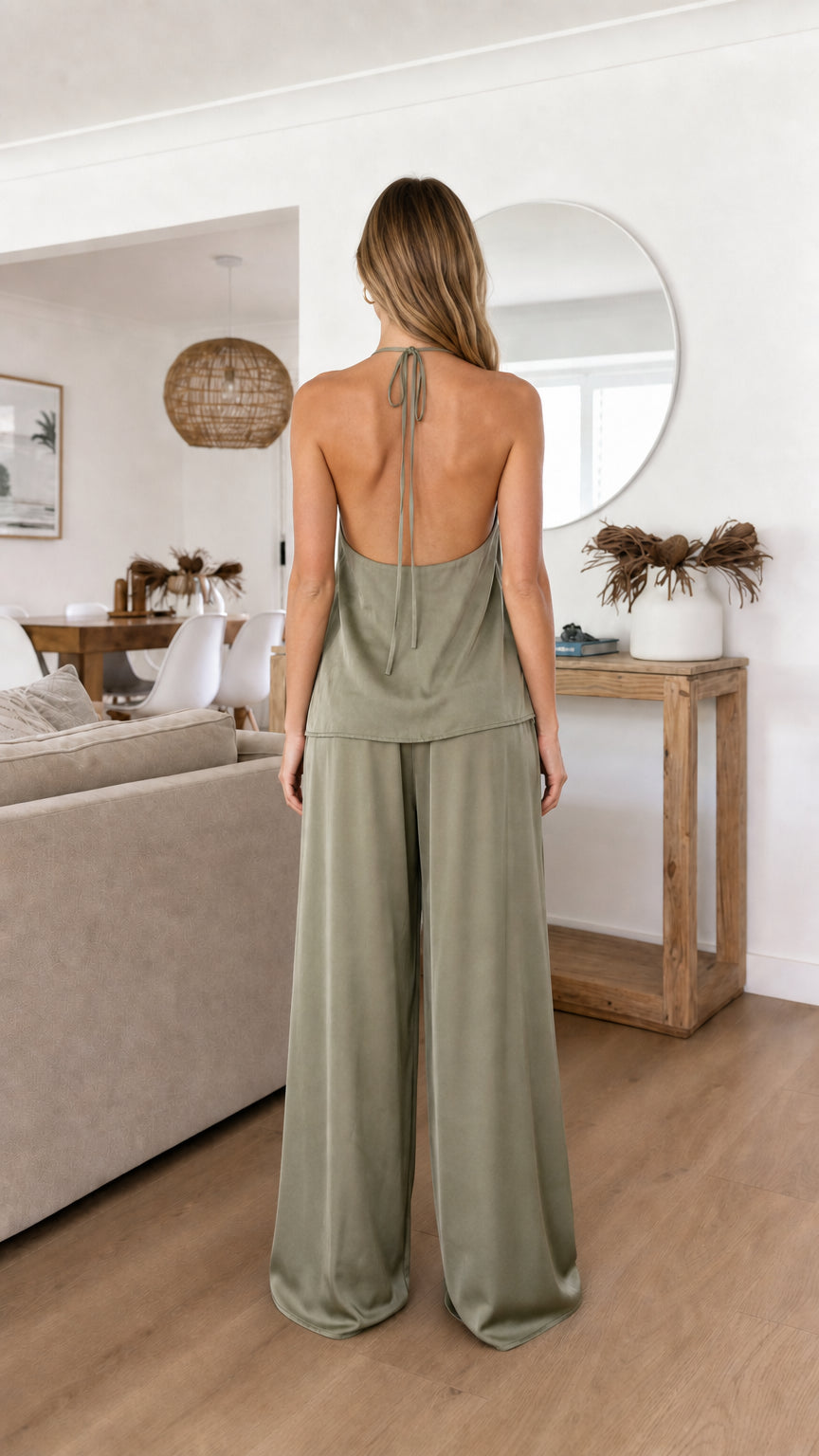 Back view of model in sage green satin halter top and trousers