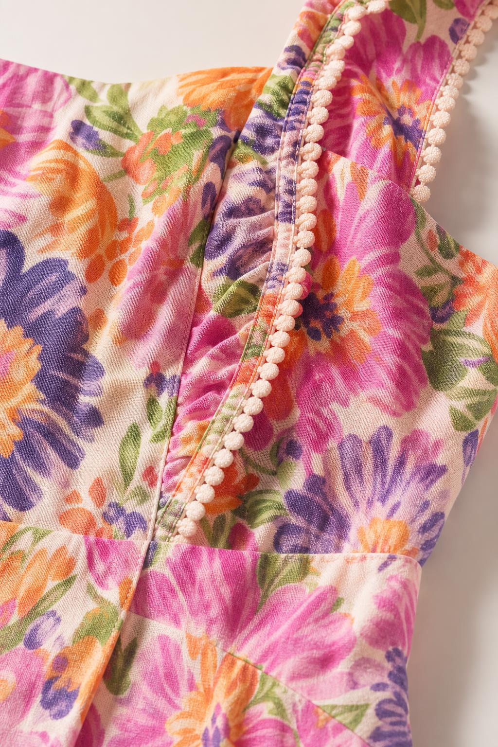 Close-up detail of fabric, pom-pom trim, and floral print