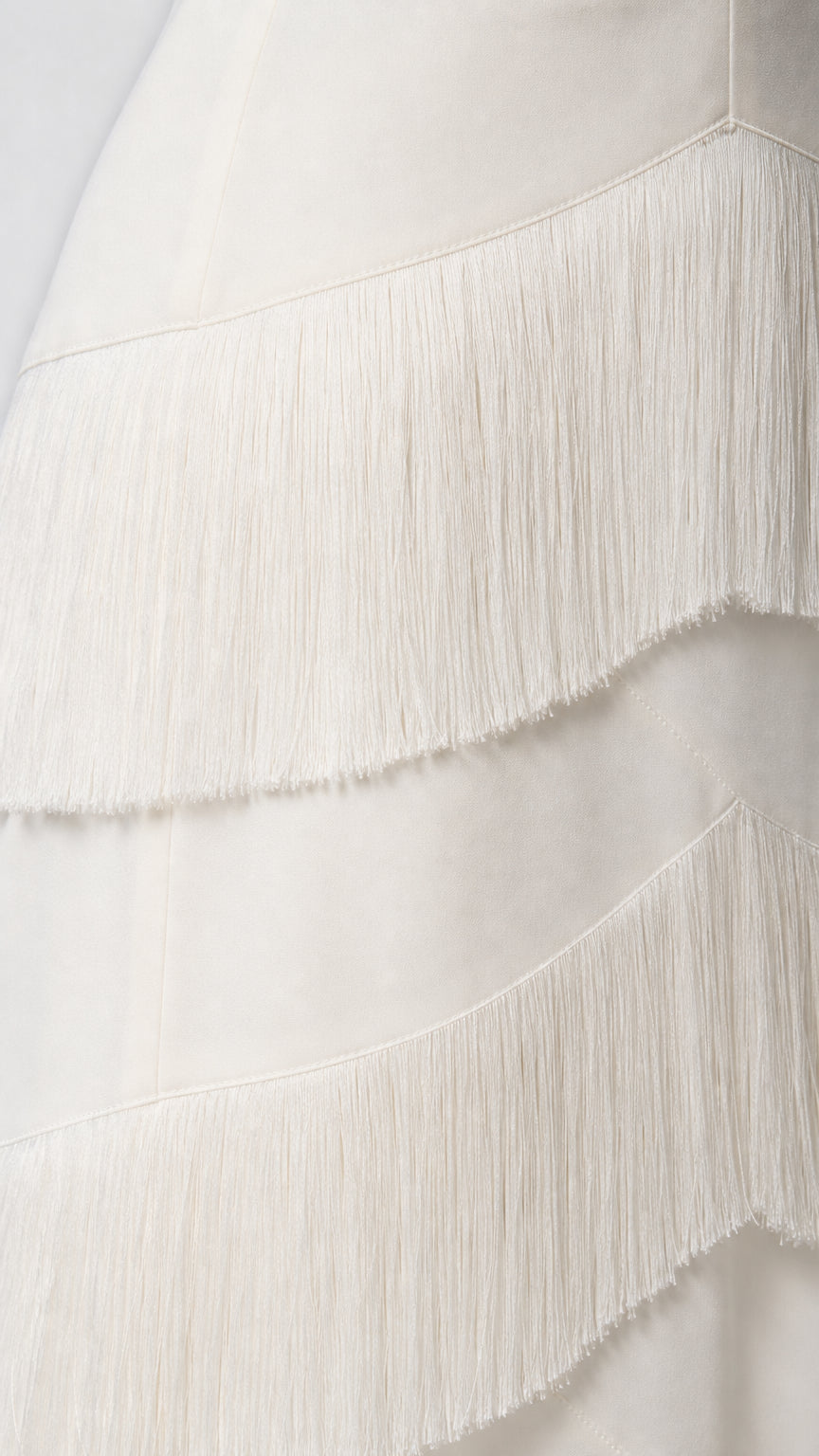 Close-up detail of the fringe texture on the white dress