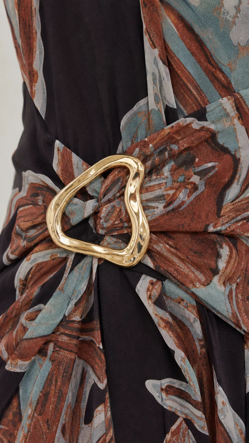 Close-up detail of gold-tone O-ring belt and fabric texture