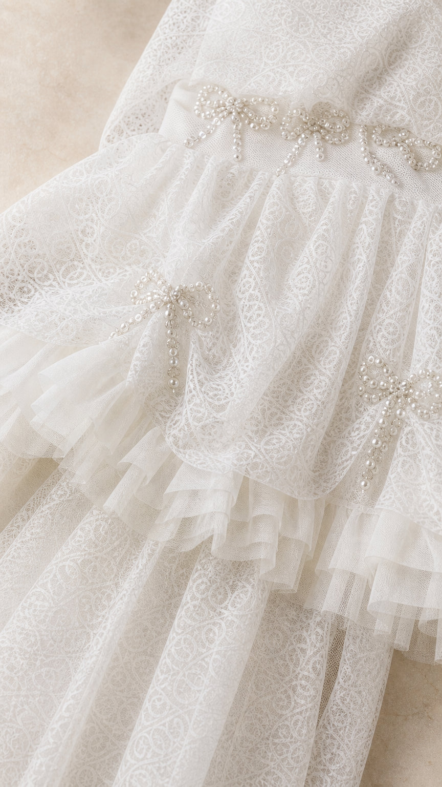 Close-up detail of rhinestone bow embellishments and ruffled lace texture