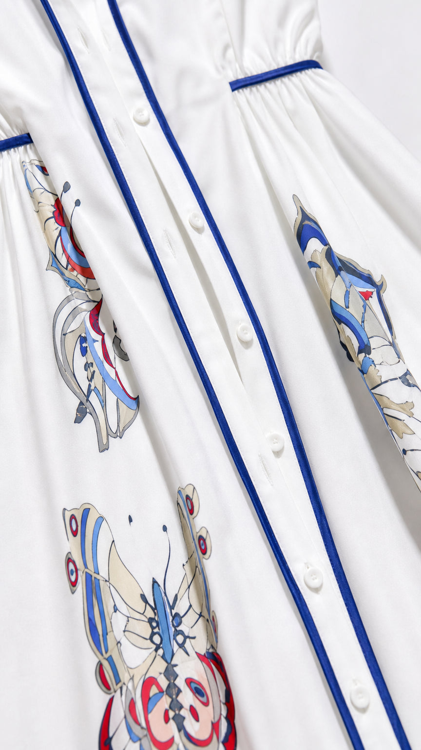 Close-up detail of button placket and butterfly print on white dress