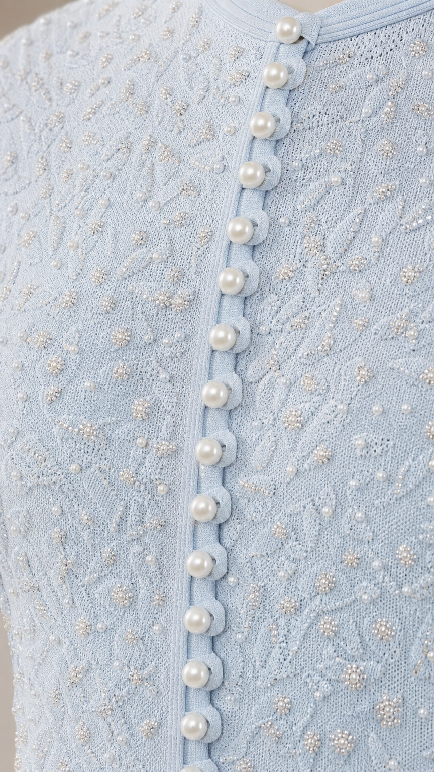 Close-up of textured knit fabric and pearl buttons on light blue dress