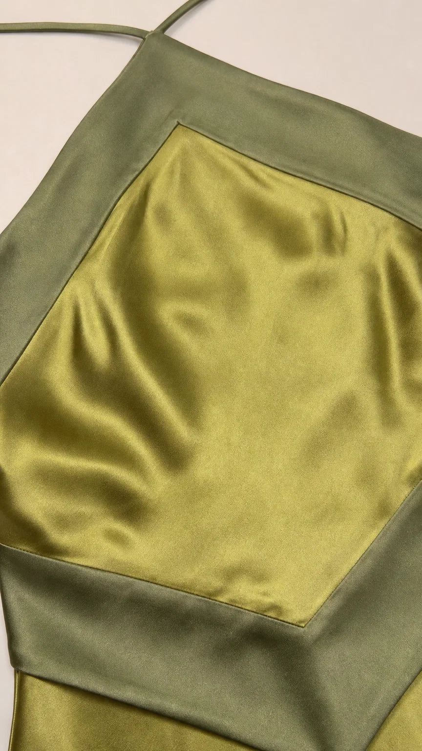 Close-up detail of olive satin fabric and geometric neckline
