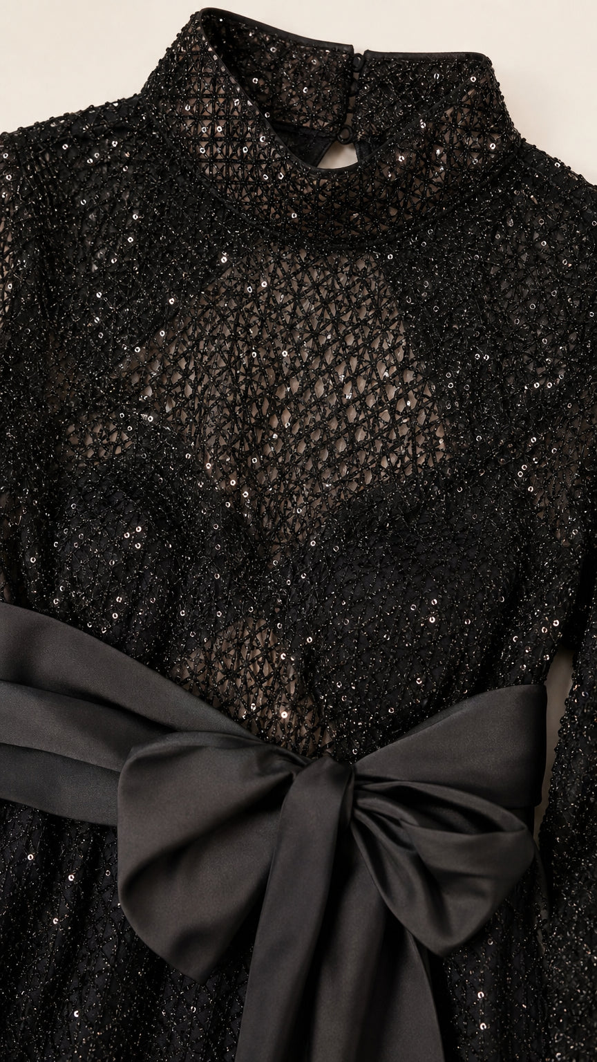 Close-up detail of mock neck, sequin mesh texture, and satin bow