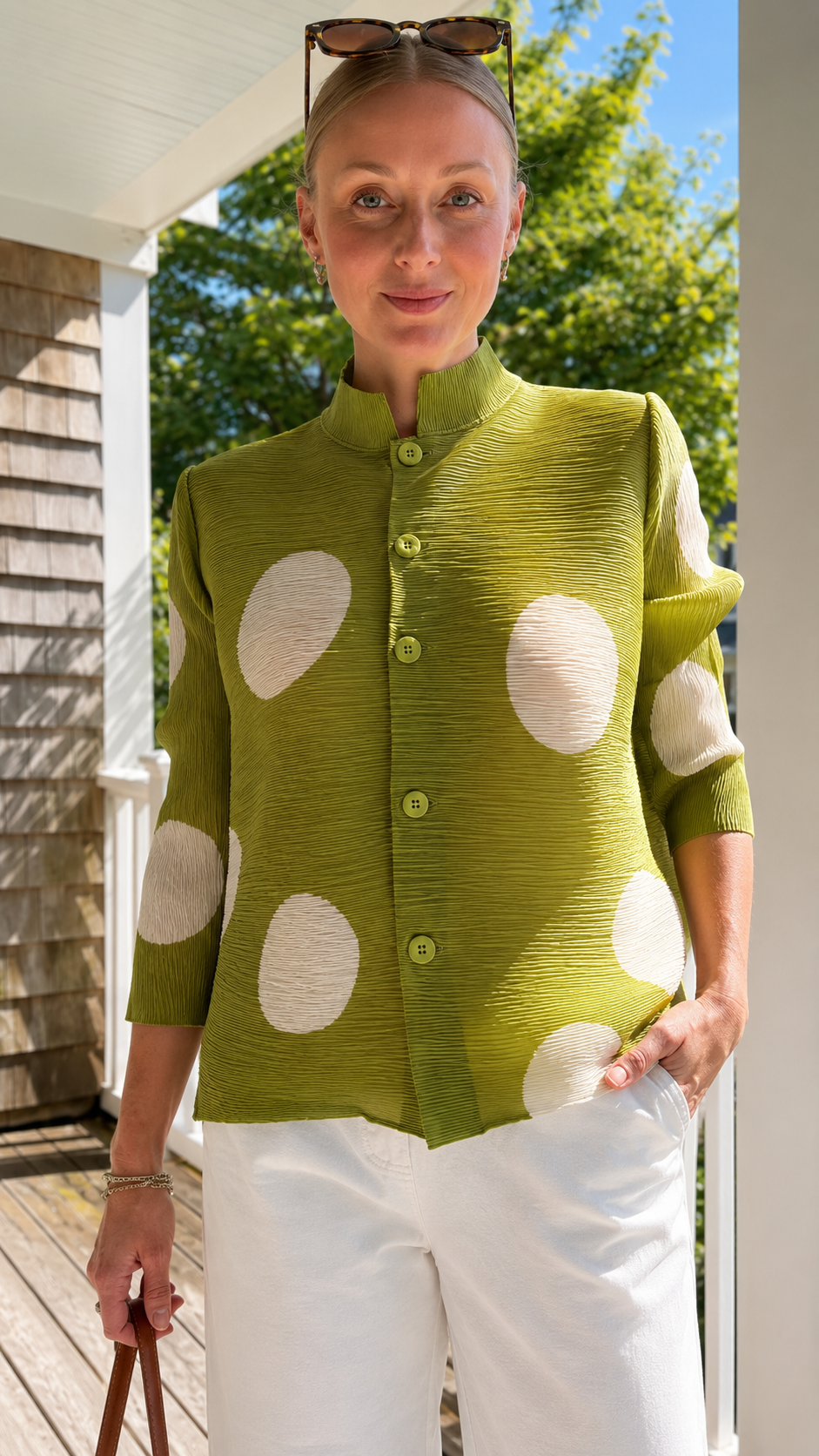 Close-up of olive green pleated polka dot jacket top showing stand collar and button-front detail