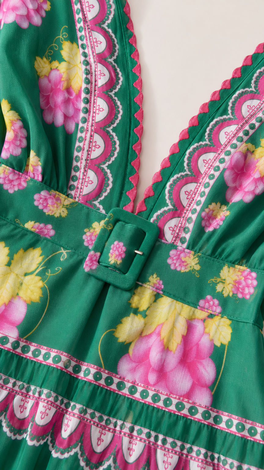Close-up detail of V-neckline and belt on green floral dress