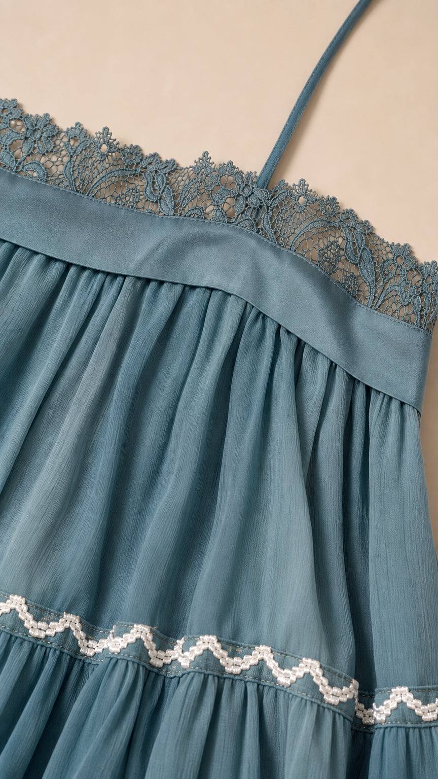 Close-up detail of lace neckline and embroidered tier on blue dress