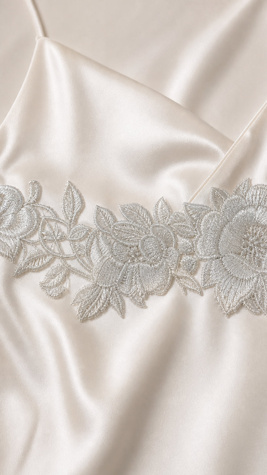 Close-up detail of white satin fabric and floral lace embroidery