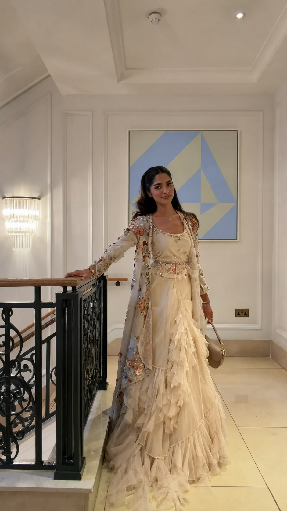 Woman wearing a champagne ruffle floor-length gown with a floral embroidered cape