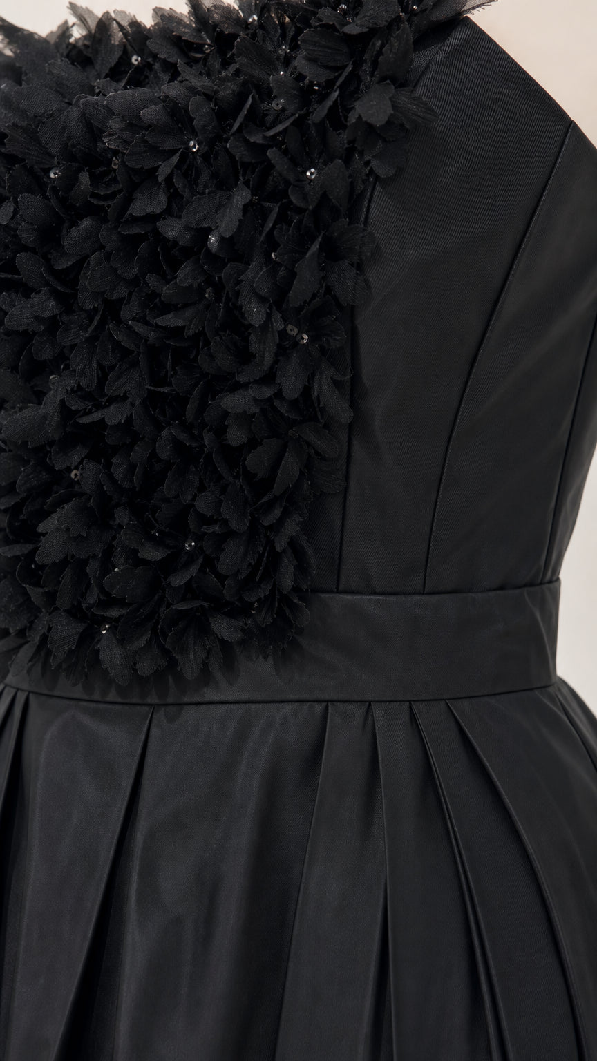 Close-up detail of textured floral bodice and pleated skirt