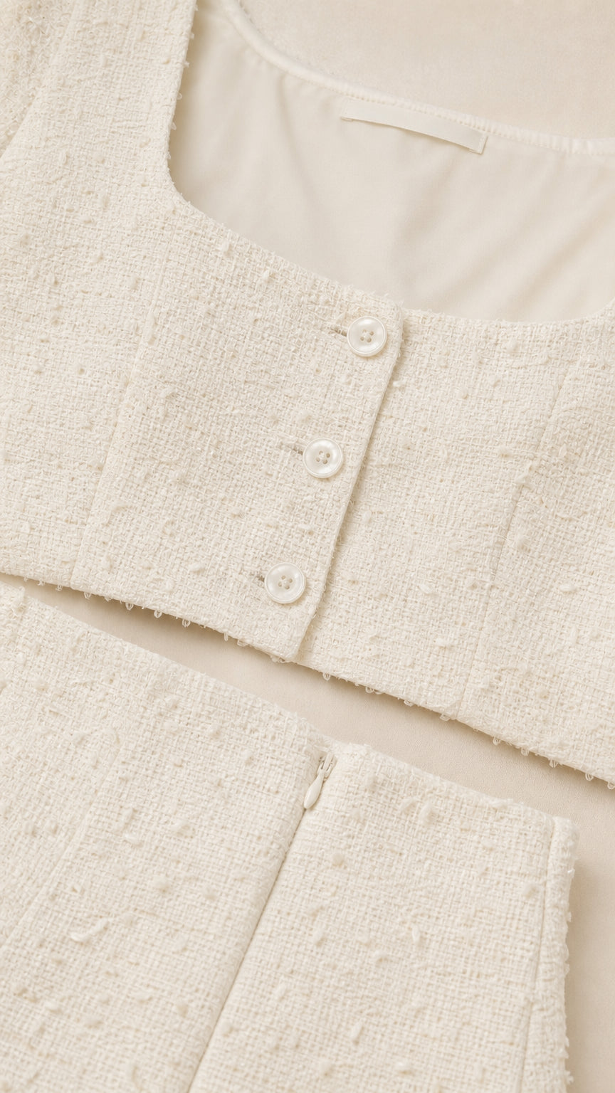 Close-up detail of white tweed top buttons and skirt zipper