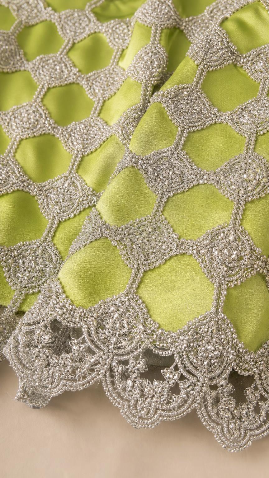 Close-up detail of metallic lattice beadwork and scalloped hem