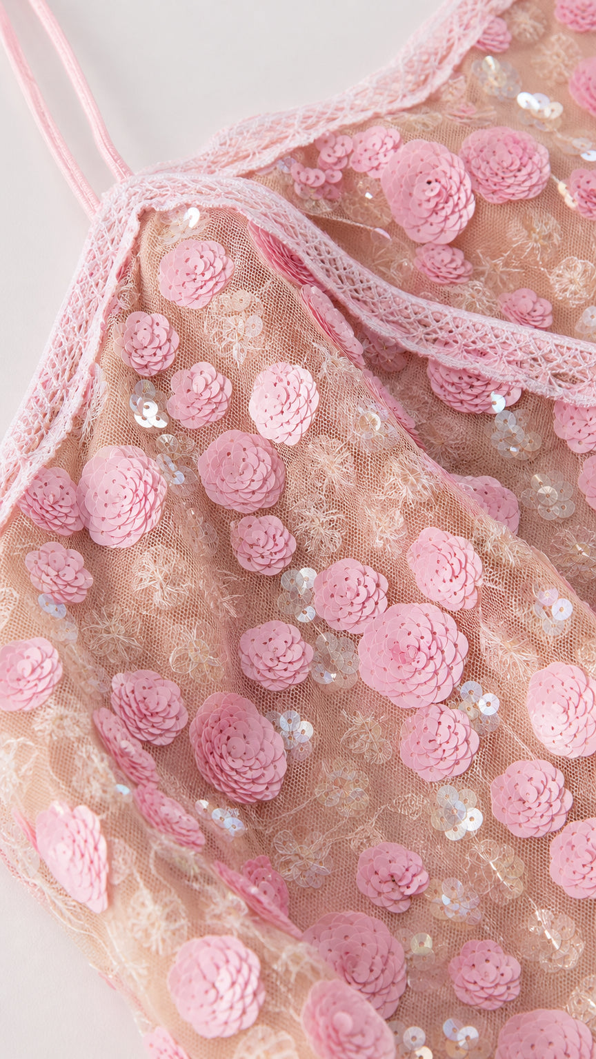Close-up detail of pink dress bodice with floral appliques and straps