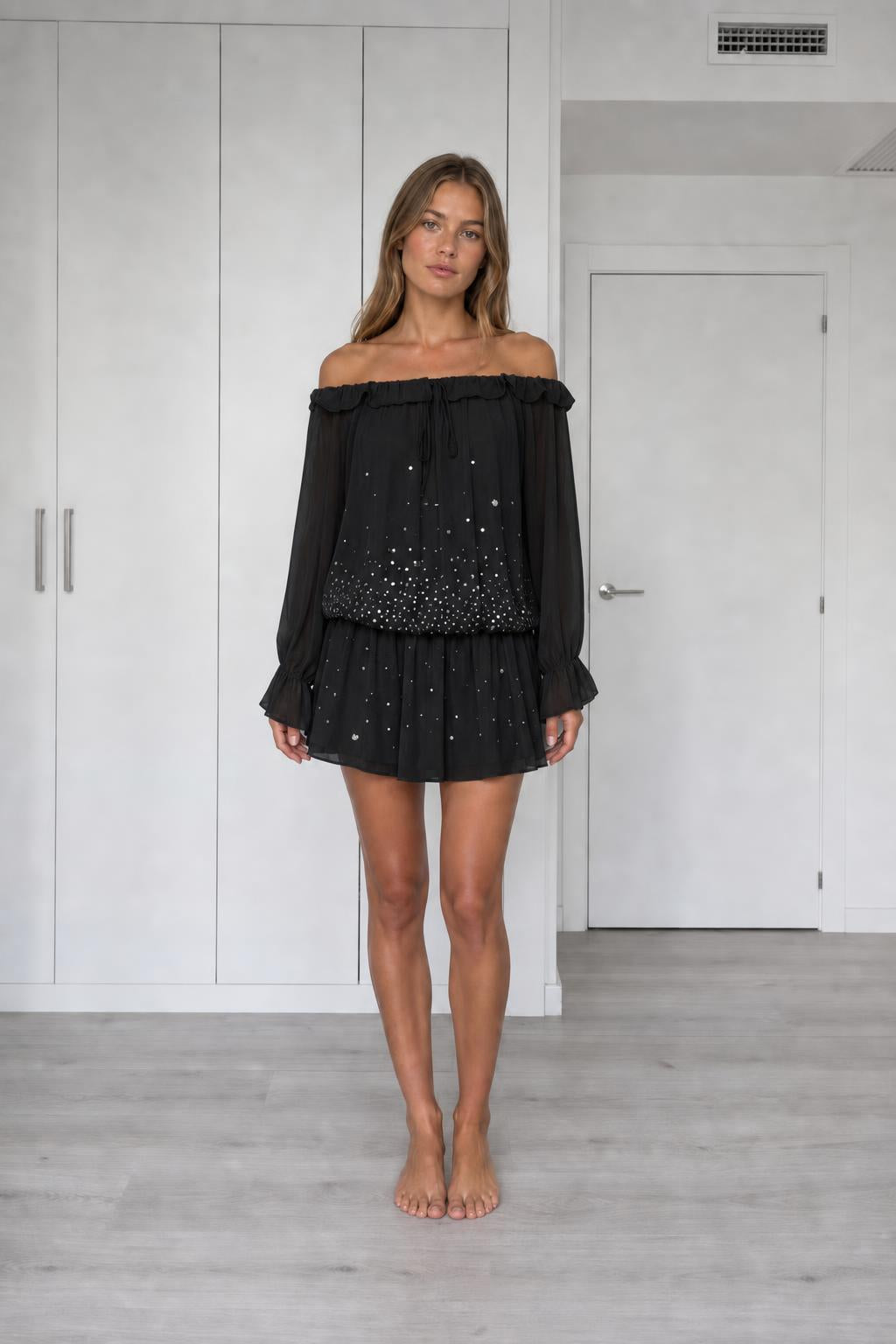 Front view of model wearing black off-the-shoulder chiffon mini dress