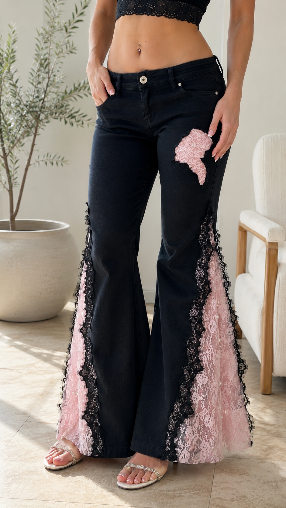 Close-up front view of black flare jeans showing floral appliqué and lace panel detail