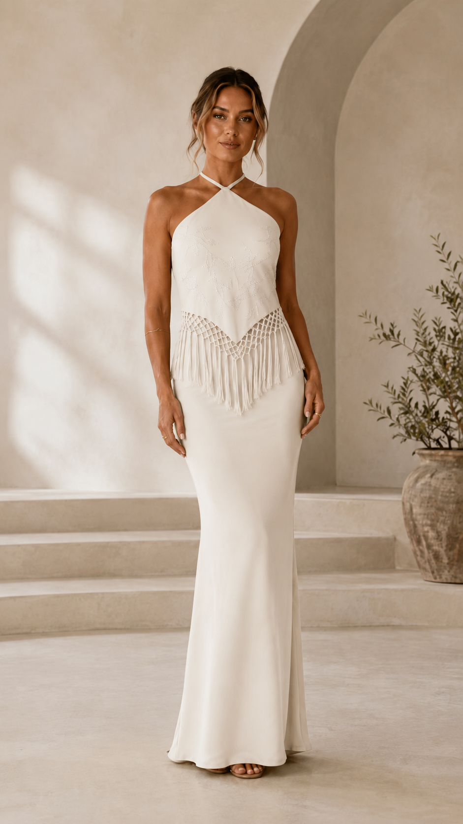 Front view of ivory halter mermaid maxi dress with fringe waist detail