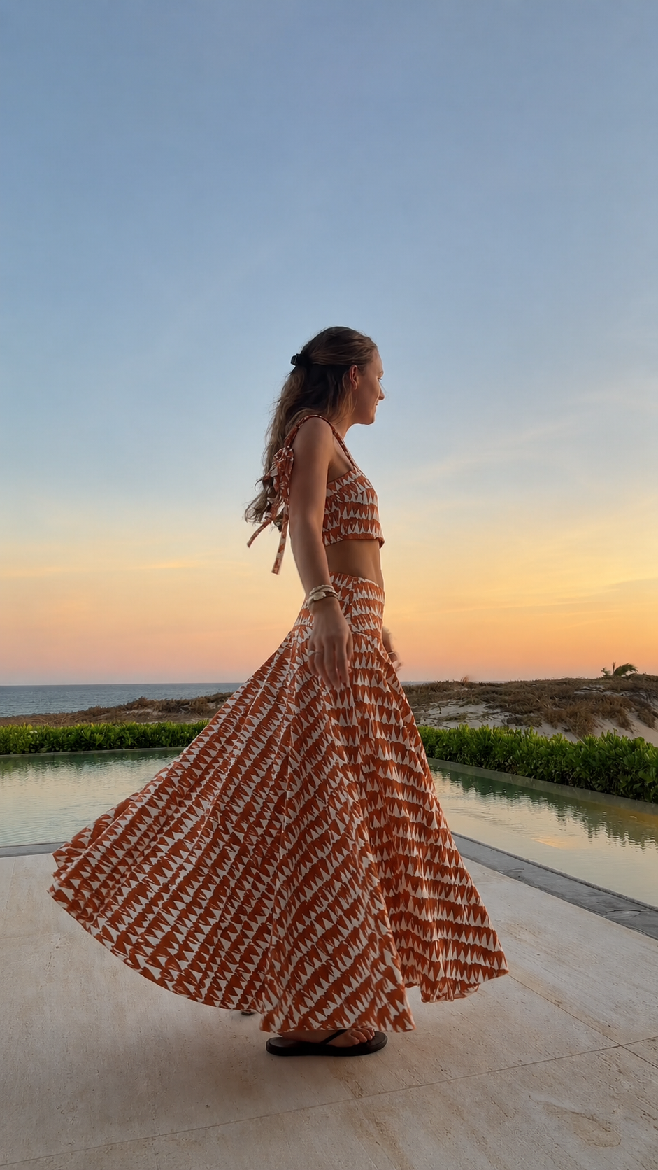 Side view of rust printed crop top and sweeping maxi skirt set